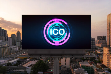 ICO hologram icon on billboard over panorama city view of Bangkok at sunset. The hub of blockchain...