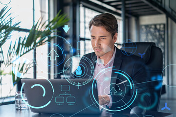 Handsome businessman in suit at workplace working with laptop to optimize development by implying...