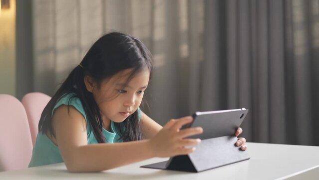 asian child student learning slide touch screen on computer tablet or kid girl video call to study online class or person smiling learn from home by pad for education on back to school by homeschool