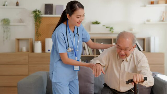 Asian young woman nurse helping senior elderly man physical therapy walk with crutches. Physiotherapist, Rehabilitation Doctor, Assist Disabled Patients. older people healthcare concept. non artwork .