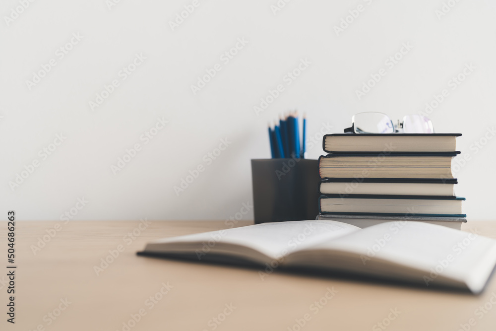 Wall mural open book and stack of textbook on table. business success idea of learning, planning or working. ed