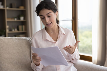 Confused woman hold documents, read official paper letter about bank debt, unexpected financial...