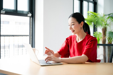 Portrait of beautiful young asian woman working on laptop in workplace.