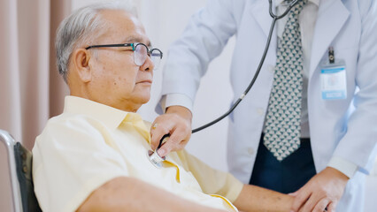 Asian senior patient having medical exam with doctor in hospital. Doctor listening heartbeat of male patient
