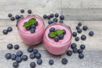 Healthy breakfast of smoothie, dessert, yogurt or milkshake with fresh blueberry on gray, dark wooden table.