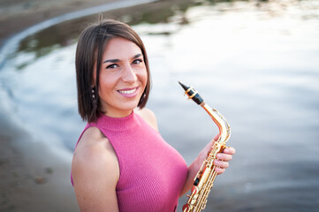 Woman playing the saxophone at sunset.