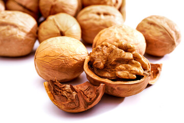 Pile of walnuts and one opened walnut isolated on white background