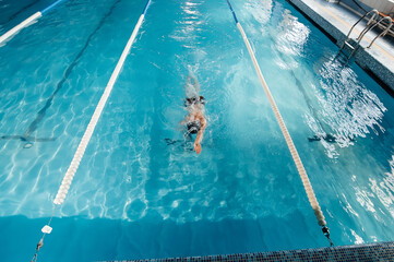 A young man trains and swims in a modern swimming pool. Sports development. Preparation for...