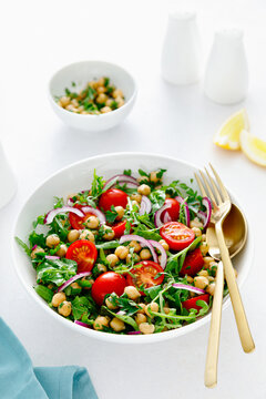 Vegetarian chickpea salad with tomatoes, arugula, parsley, spinach and red onion. Healthy food, diet