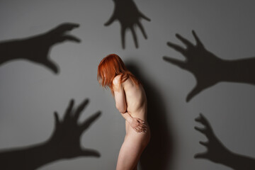 sexual harassment or abuse concept with naked woman shadows of grabbing hands