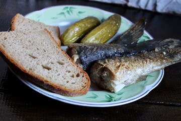 fried fish, pickles and slices of bread on a plate