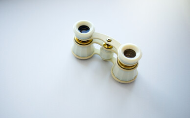 Mother-of-pearl theatrical binoculars on a white background. An ad for an opera or theater on a...