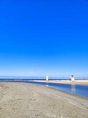 The Black Sea in spring with waves and sand on the beach with a bright blue sky.