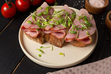 Toast on fresh toasted bread with cream cheese, ham and microgreens, open space