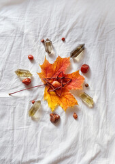 minerals and autumn maple leaf on fabric background. wicca mandala for fall season. witch magic...