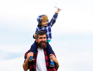Portrait of happy father giving son piggyback ride on his shoulders. Child play with toy plane. Family travel vacation, father's day.