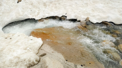 The frozen snow of water coming from the spring in the mountains in the summer season