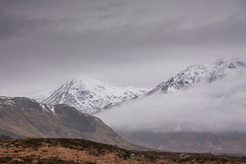 Beautiful Winter landscape of Buachaille Etive Mor Stob Dearg in Scottish Highlands engulfed in low cloud with snowcapped peaks