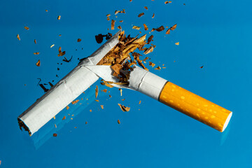 Broken cigarette on blue background. Stop smoking concept photography