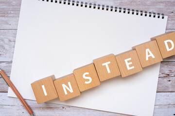 「INSTEAD」と書かれた積み木、ノート、ペン