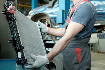 In the hands of an auto mechanic, an automobile radiator. Inspection and control of compliance,...