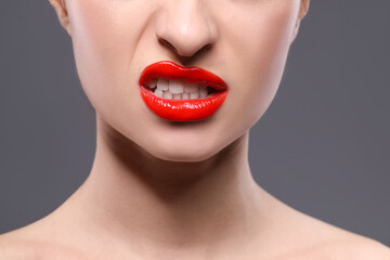 Obraz premium Young woman with beautiful red lips on grey background, closeup