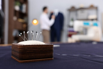 Dressmaker working in atelier, focus on pin cushion. Space for text