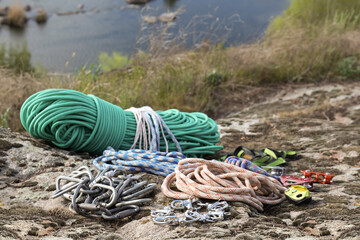 Different ropes and other climbing equipment on rock near river