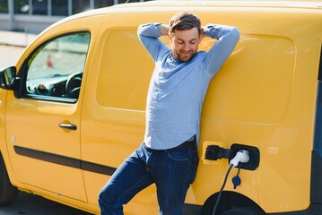 Man Charging Electric Vehicle With Cable