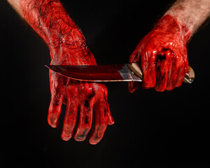 Man holding knife with bloody hand on black background.  © Михаил Решетников
