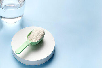 Spoon of natural lemon collagen protein powder on podium and blue background. Trendy food additives for skin regeneration. Copy space