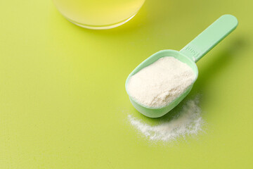Collagen or protein powder on measure spoon. Skin care, wellness. Copy space, green background