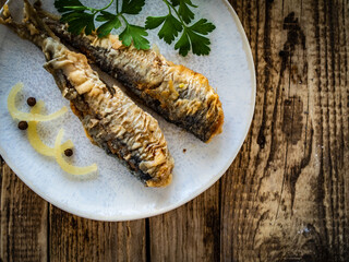 Fish dish - marinated fried herrings on wooden table
