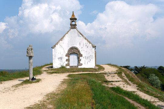 The Saint-Michel tumulus in Carnac, with its chapel and its calvary; under a slightly cloudy blue sky