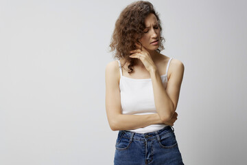 Unhappy sad nervous curly beautiful woman in basic white t-shirt fold hands looks aside thinking about problems posing isolated on over white background. People Emotions Lifestyle concept. Copy space
