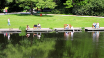 Effekt mit geringem Schärfebereich: Verschwommene Personen im Park im Sommer auf einem Steg