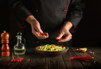 The chef prepares a salad for breakfast or lunch in the kitchen. Vegetarian cuisine for the hotel