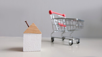 wooden decorative house in a shopping trolley, copy space, sale and purchase of real estate concept