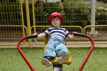 Child playing on outdoor playground. Kids play on kindergarten yard. Active kid on colorful slide.  Funny toddler boy having fun on colorful slide 