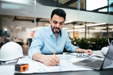 Busy smiling smart attractive millennial muslim male designer with beard working on project in...
