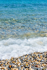 Sea waves on the coast. Transparent sea water and pebbles. Seaside resort for summer vacation