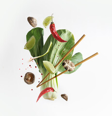 Asian food concept with flying ingredients: Bok choy , chopsticks, lime, shiitake, spices and chili...