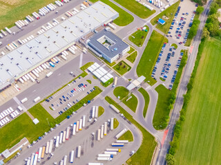 Aerial view of a logistics park with warehouse, loading hub and many semi trucks with cargo...