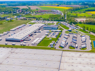 Aerial view of a logistics park with warehouse, loading hub and many semi trucks with cargo...
