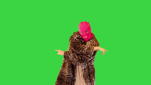 Active girl in pink balaclava performs energetic dance on a Green Screen, Chroma Key.