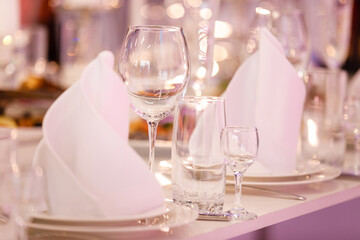 Empty glass set in restaurant. wedding, decor, celebration, holiday concept - romantic table setting with white tablecloth, plates, crystal glasses