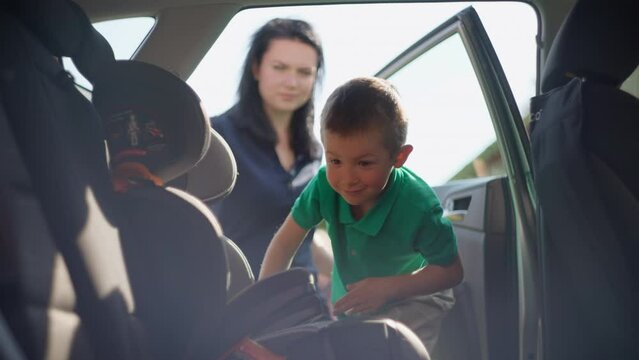 The boy gets into the car seat. Mom fastens the child in the car seat. High quality 4k footage