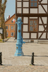 Old traditional blue water pump with gryphon head and crest from Stettin city emblem. old water pump - obrazy, fototapety, plakaty