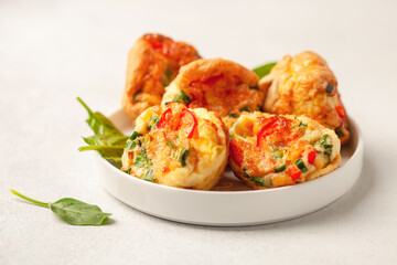 Egg muffins ( bites) and spinach leaves  in a plate on a gray background
