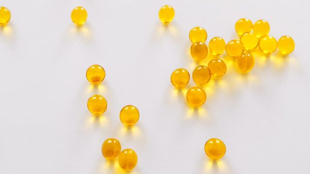 Vitamin D, A, E or omega 3 fish oil in the yellow pill concept. Golden capsules on the white background. 